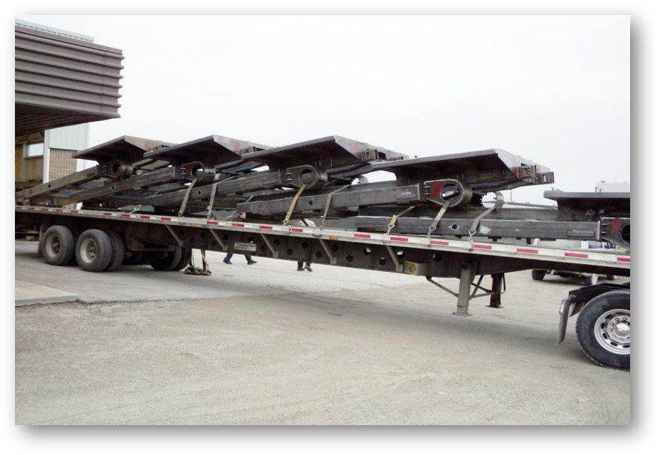 Series of machined parts on a flat truck bed.